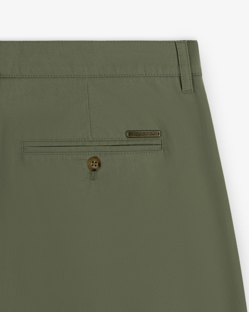 Close-up of Lightweighted Pleated Cotton Trouser in olive green with a buttoned back pocket and metallic brand tag.