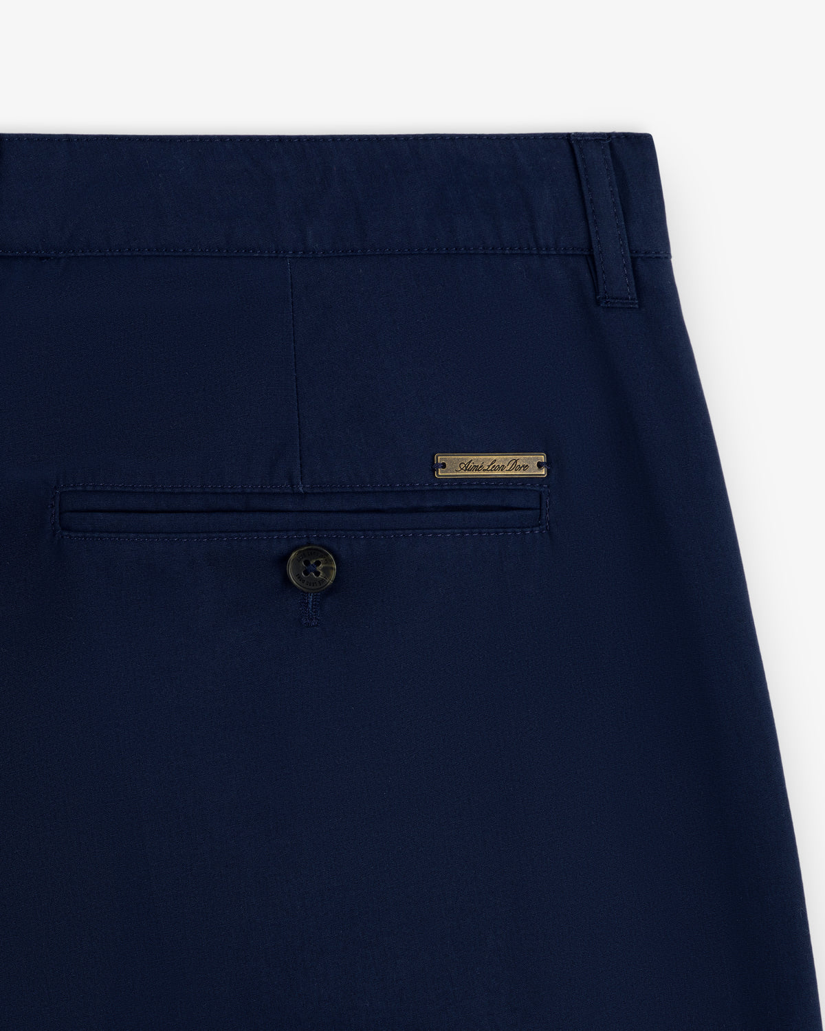 Close-up of Lightweighted Pleated Cotton Trouser's navy back pocket with button and small metal brand label above.