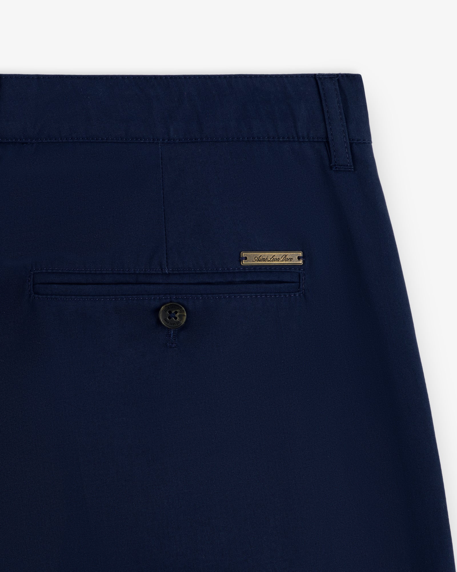 Close-up of Lightweighted Pleated Cotton Trouser's navy back pocket with button and small metal brand label above.