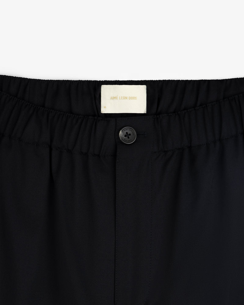 Close-up of Elasticated Waist Gabardine Trouser in black with an elastic waistband, button, and visible white label inside.
