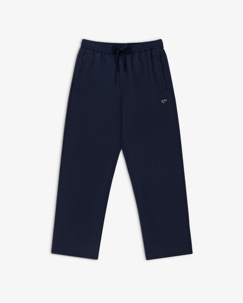 Crest Nylon Track Pant in navy blue with side pockets and a small logo on the left thigh, shown laid flat on white.