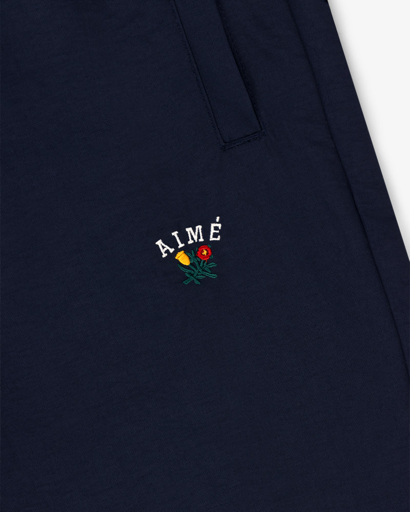 Navy blue Crest Nylon Track Pant with AIMÉ and small yellow and red flower embroidery below the pocket.