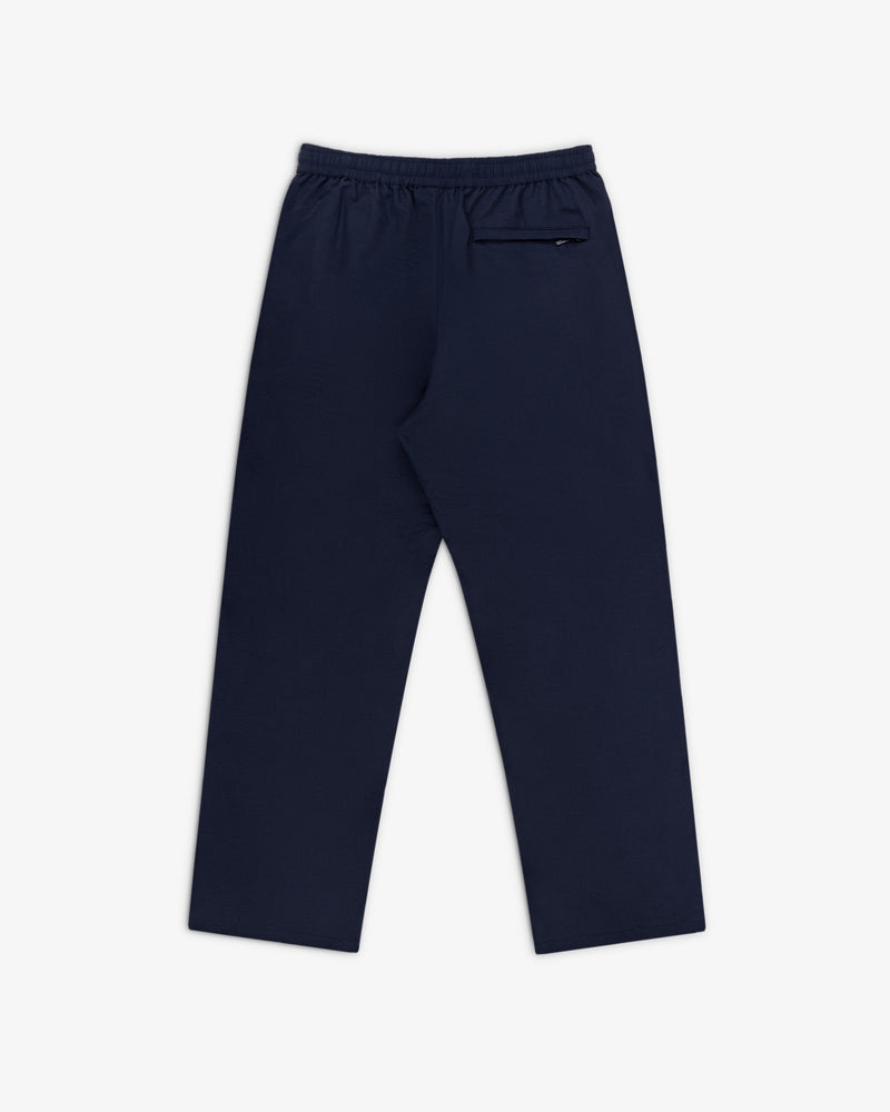 Crest Nylon Track Pant in navy blue with an elastic waistband and back zippered pocket, shown on a white background.
