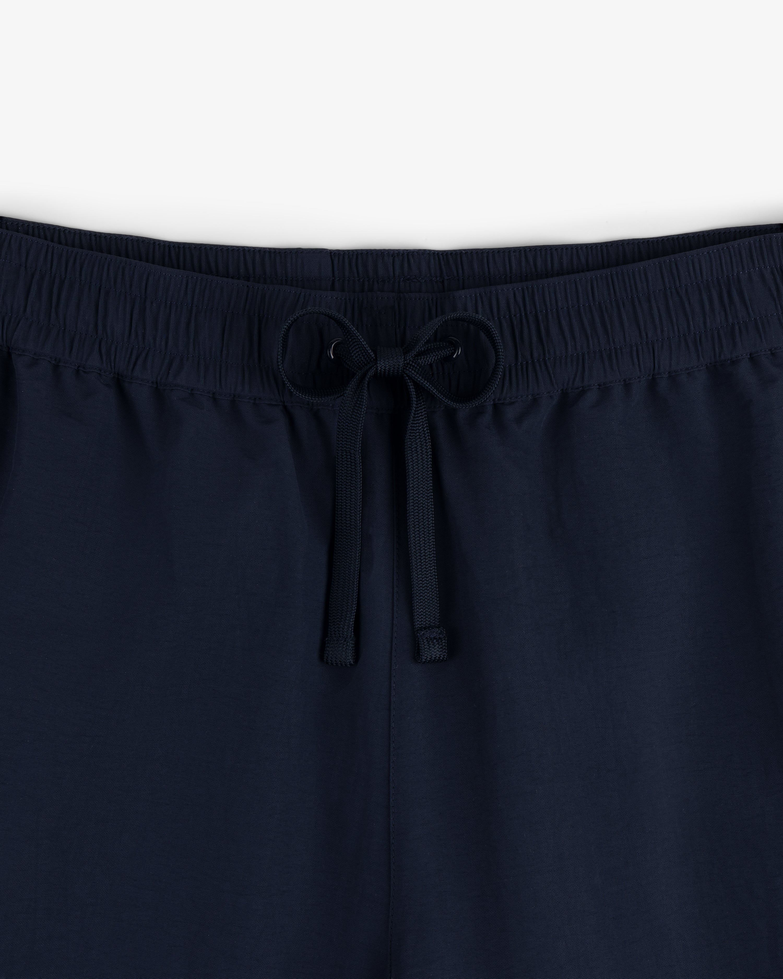 Close-up of the Crest Nylon Track Pant in navy, featuring an elastic waistband and front drawstring tie.
