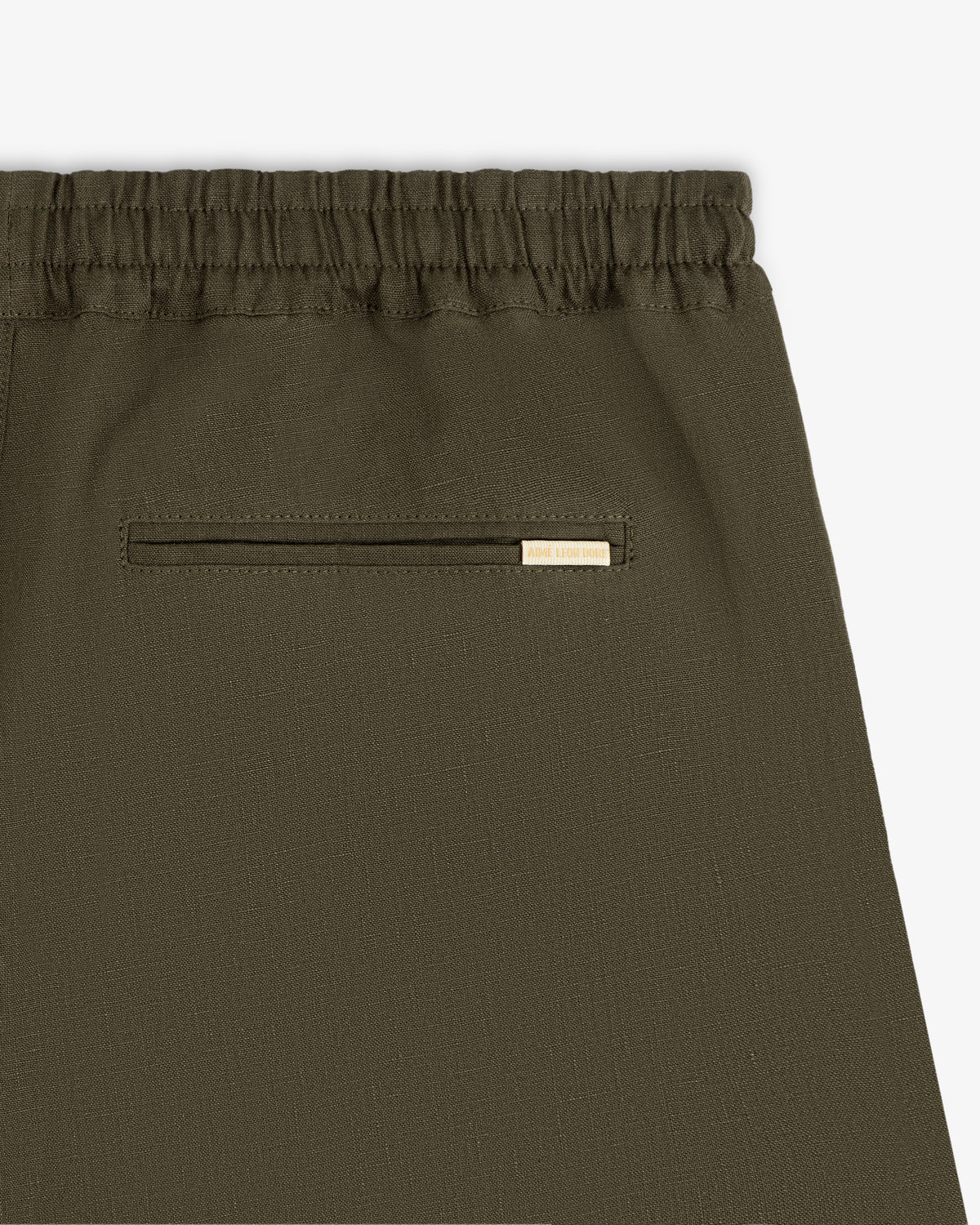 Close-up of Linen Leisure Pant in olive green with elastic waistband and small back pocket featuring metal accent.
