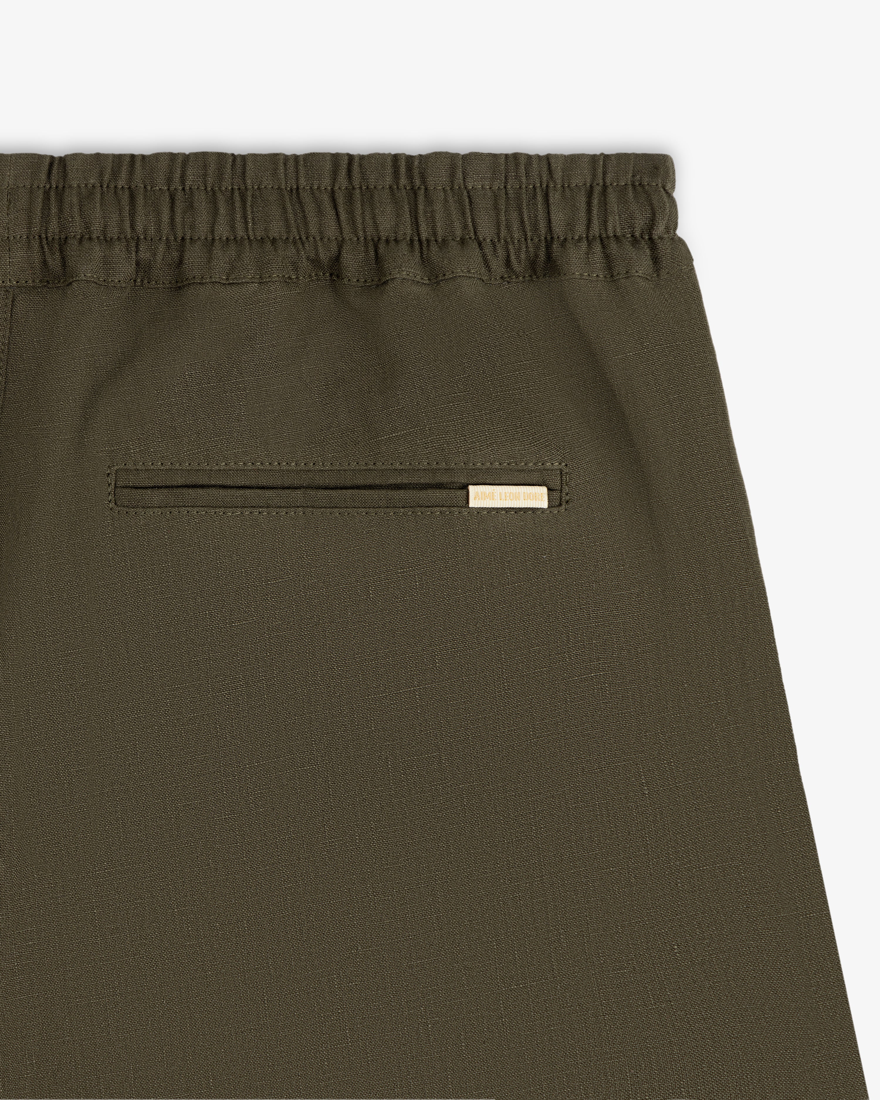 Close-up of Linen Leisure Pant in olive green with elastic waistband and small back pocket featuring metal accent.