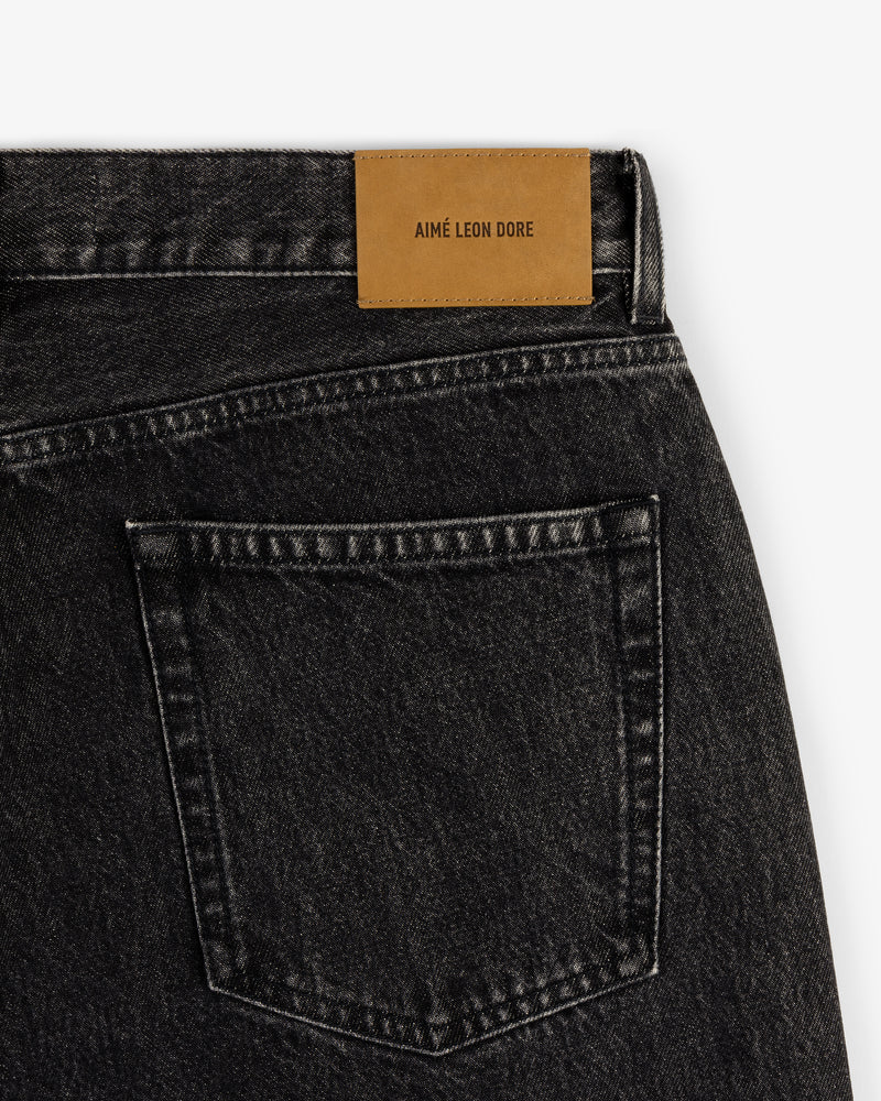 Close-up of Relaxed Fit 5-Pocket Denim Pant in black denim with a brown AIMÉ LEON DORE patch above the back pocket.