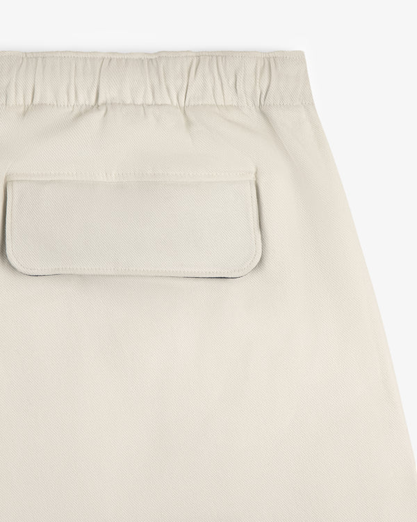 Close-up of the Crest Casual Short in beige, featuring an elastic waistband and a back flap pocket.