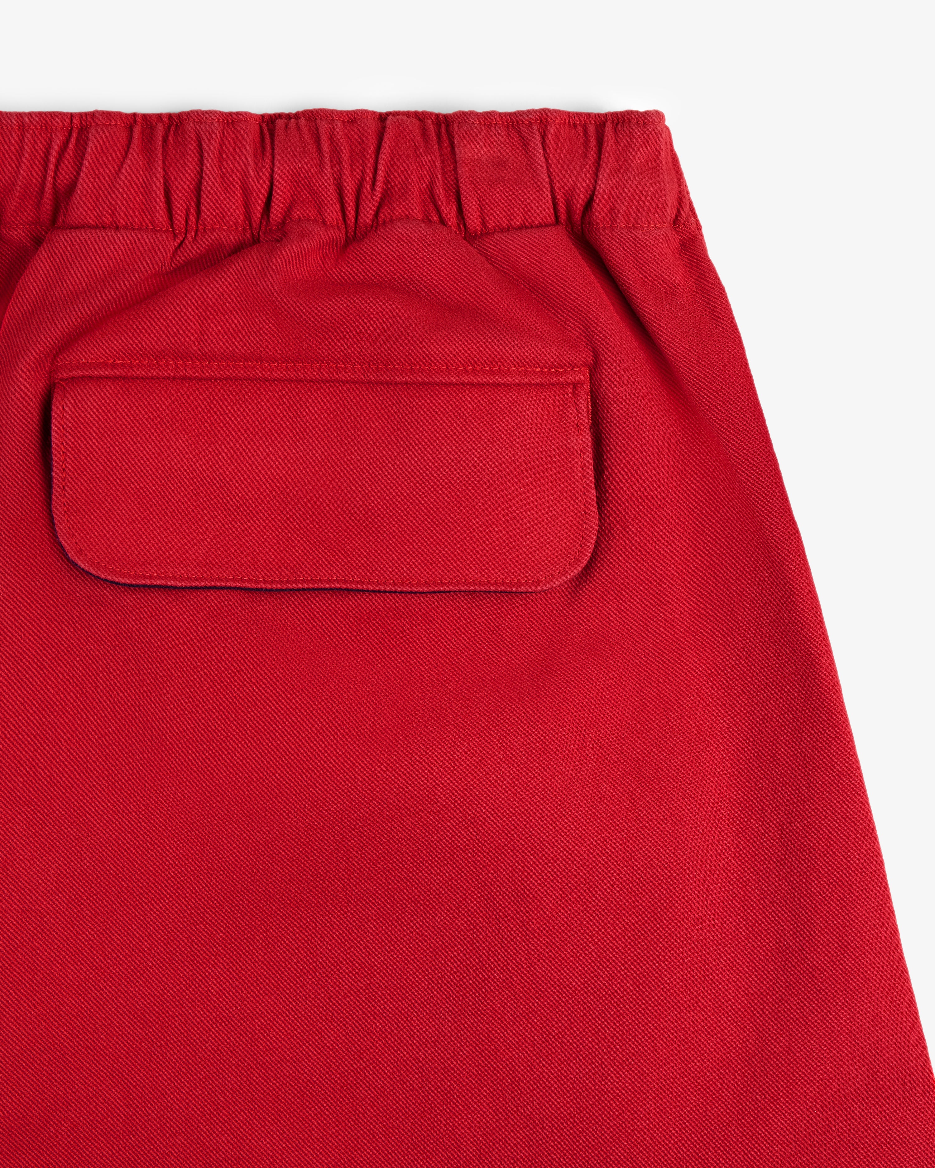 Close-up of Crest Casual Short in red, featuring an elastic waistband and a single flap back pocket.