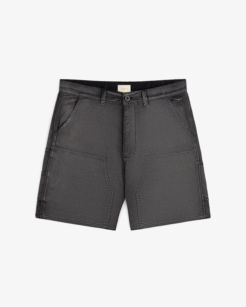 Garment Dyed Carpenter Short in dark gray with front pockets, belt loops, and a button closure, laid flat on white.