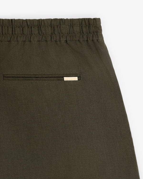 Close-up of Linen Leisure Short in olive green with elastic waistband and single back pocket with gold label.