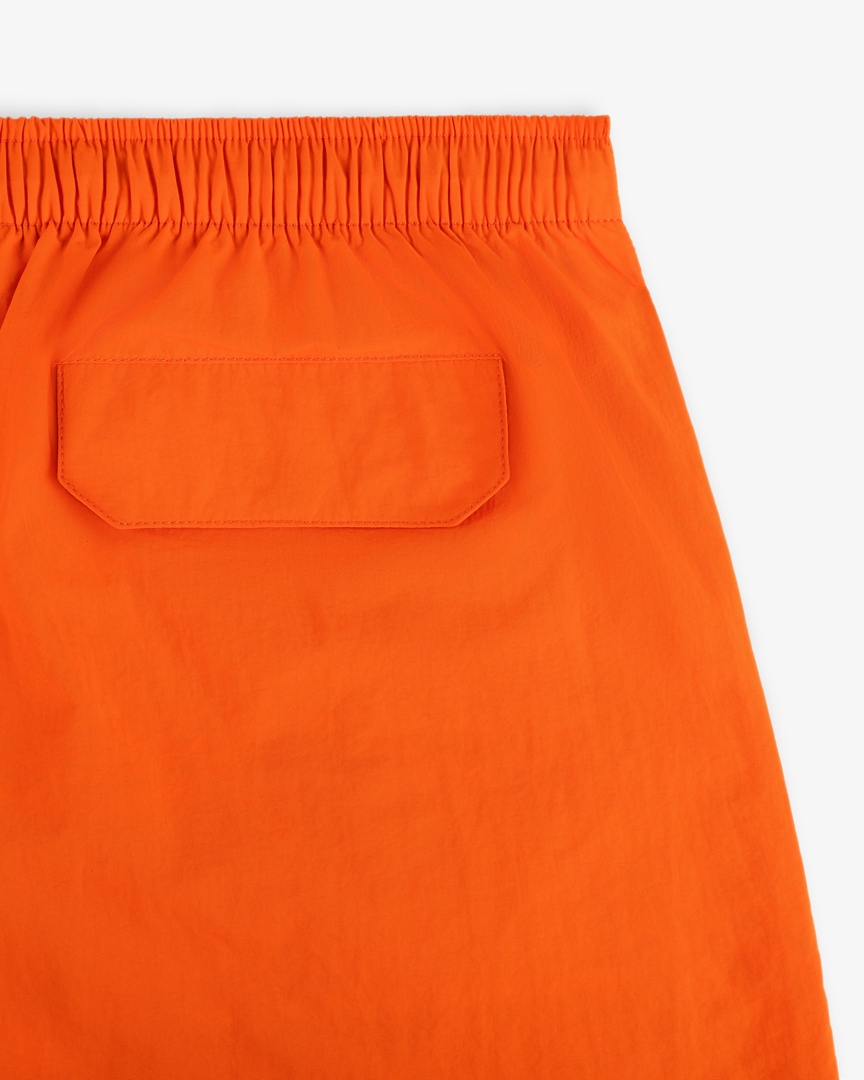 Close-up of Logo Swim Short in bright orange with an elastic waistband and a single flap back pocket.