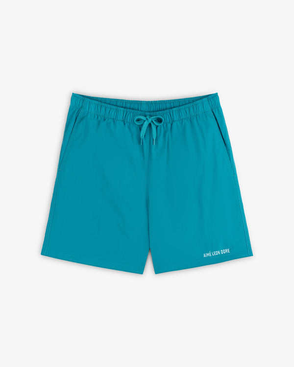 Logo Swim Short in bright turquoise with elastic waist, drawstring, side pockets, and branding near the hem.