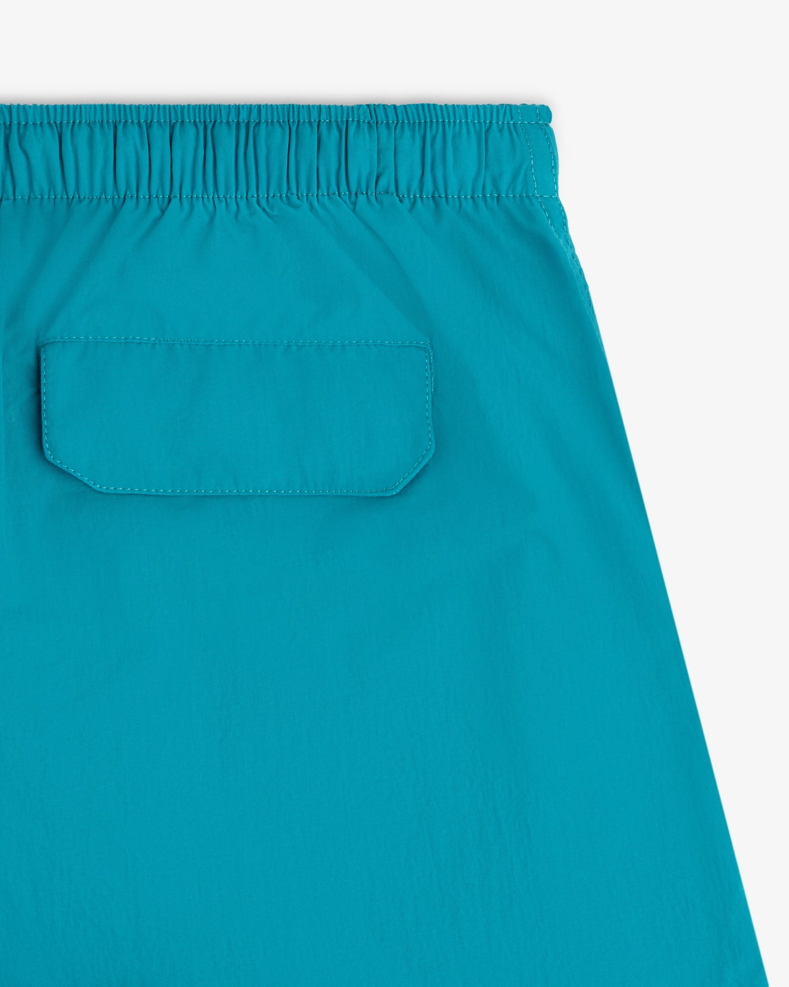 Close-up of the back pocket and elastic waistband on the bright blue Logo Swim Short against a white background.
