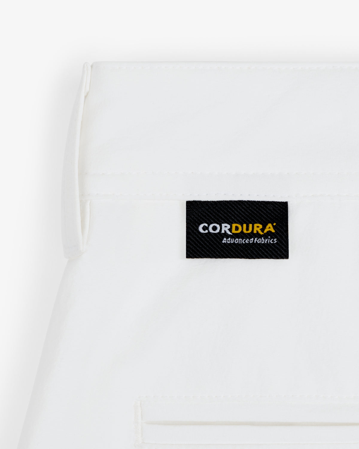 Close-up of ALD Golf Cordura Double Pleated Short in white with a black CORDURA Advanced Fabrics label above the pocket.