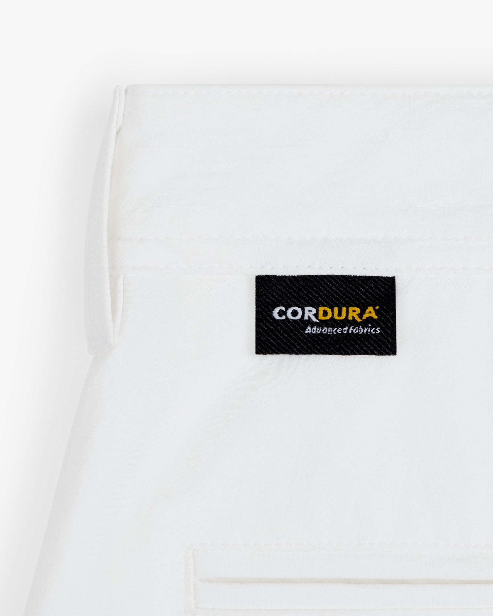 Close-up of ALD Golf Cordura Double Pleated Short in white with a black CORDURA Advanced Fabrics label above the pocket.