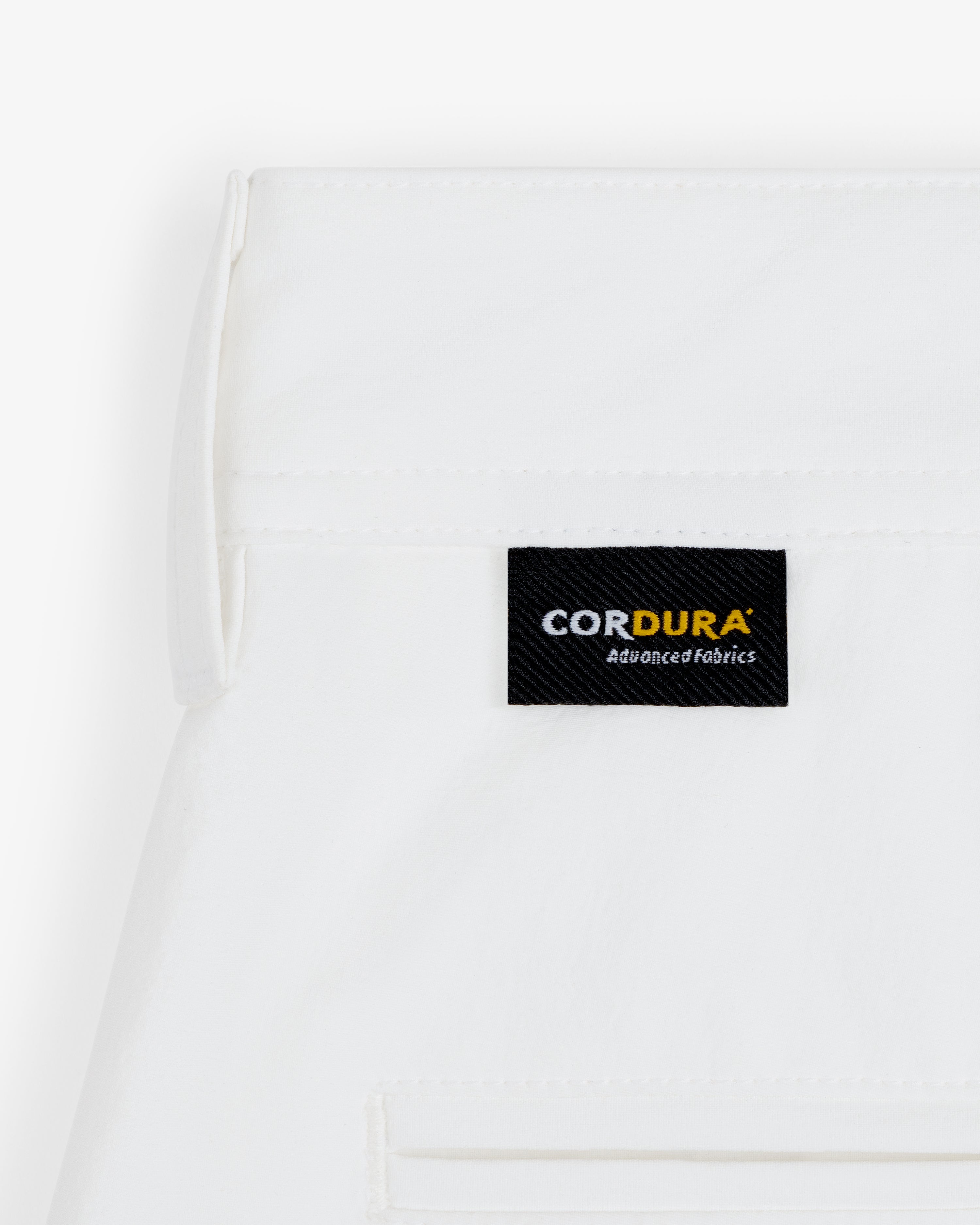 Close-up of ALD Golf Cordura Double Pleated Short in white with a black CORDURA Advanced Fabrics label above the pocket.