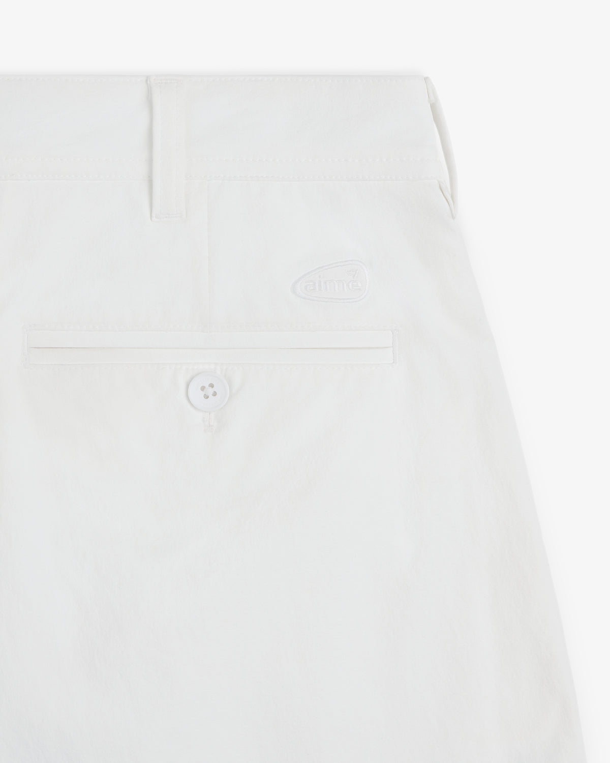 Close-up of ALD Golf Cordura Double Pleated Short in white with back pocket, button, and small aime logo above pocket.