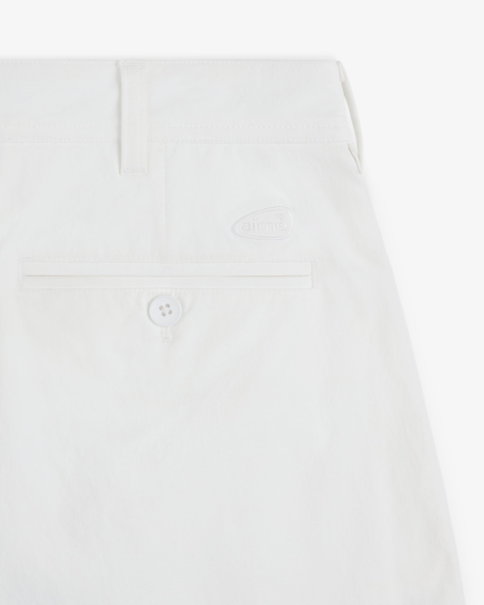 Close-up of ALD Golf Cordura Double Pleated Short in white with back pocket, button, and small aime logo above pocket.