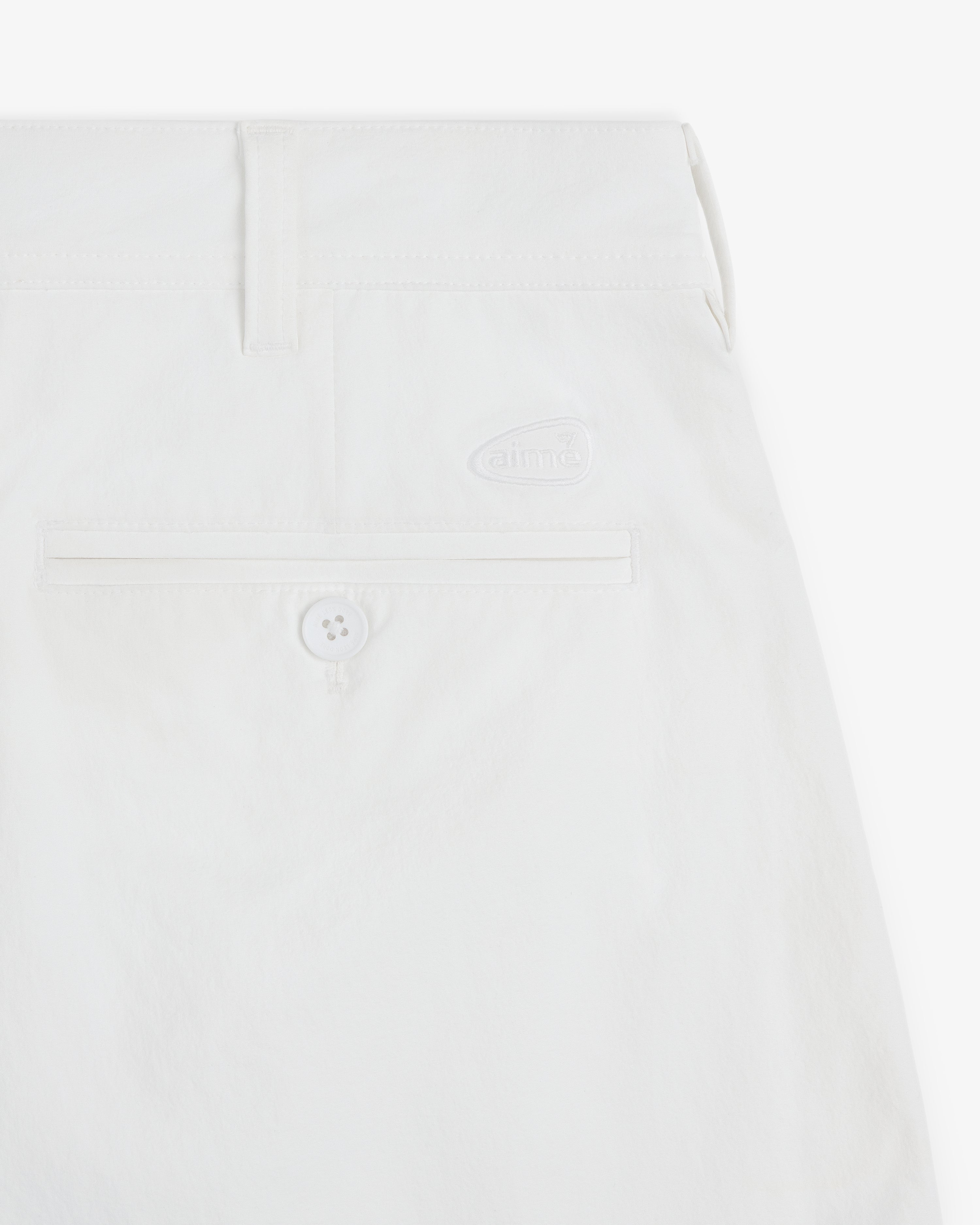 Close-up of ALD Golf Cordura Double Pleated Short in white with back pocket, button, and small aime logo above pocket.