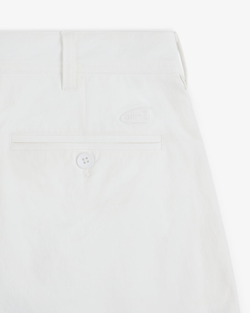 Close-up of ALD Golf Cordura Double Pleated Short in white with back pocket, button, and small aime logo above pocket.