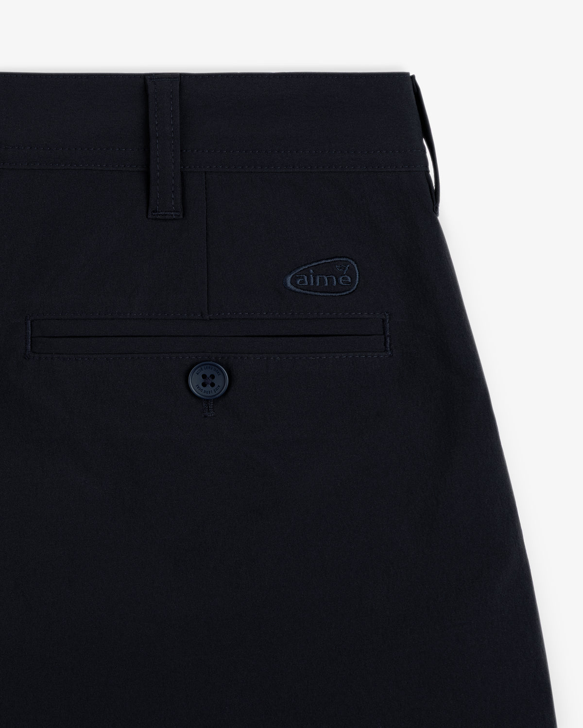 Close-up of ALD Golf Cordura Double Pleated Short in navy, showing back pocket with button and aime logo patch above.