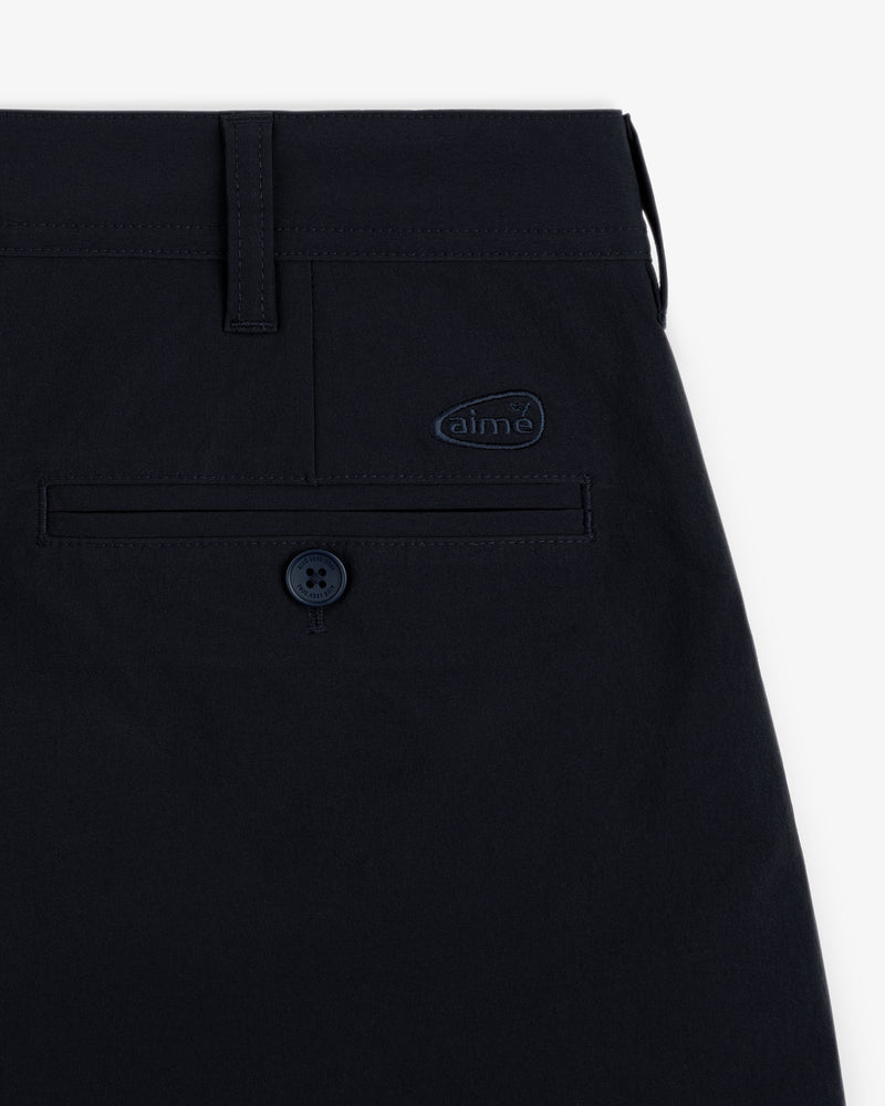 Close-up of ALD Golf Cordura Double Pleated Short in navy, showing back pocket with button and aime logo patch above.