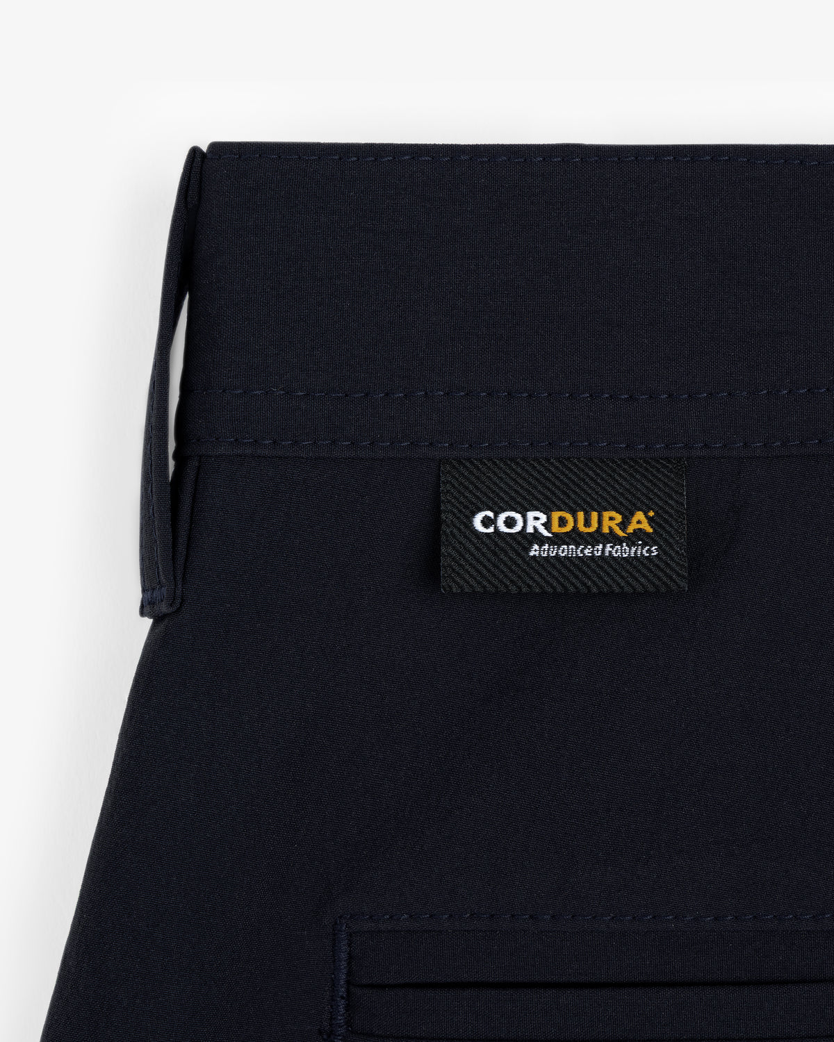 Close-up of ALD Golf Cordura Double Pleated Short in navy with a black CORDURA Advanced Fabrics label sewn on.