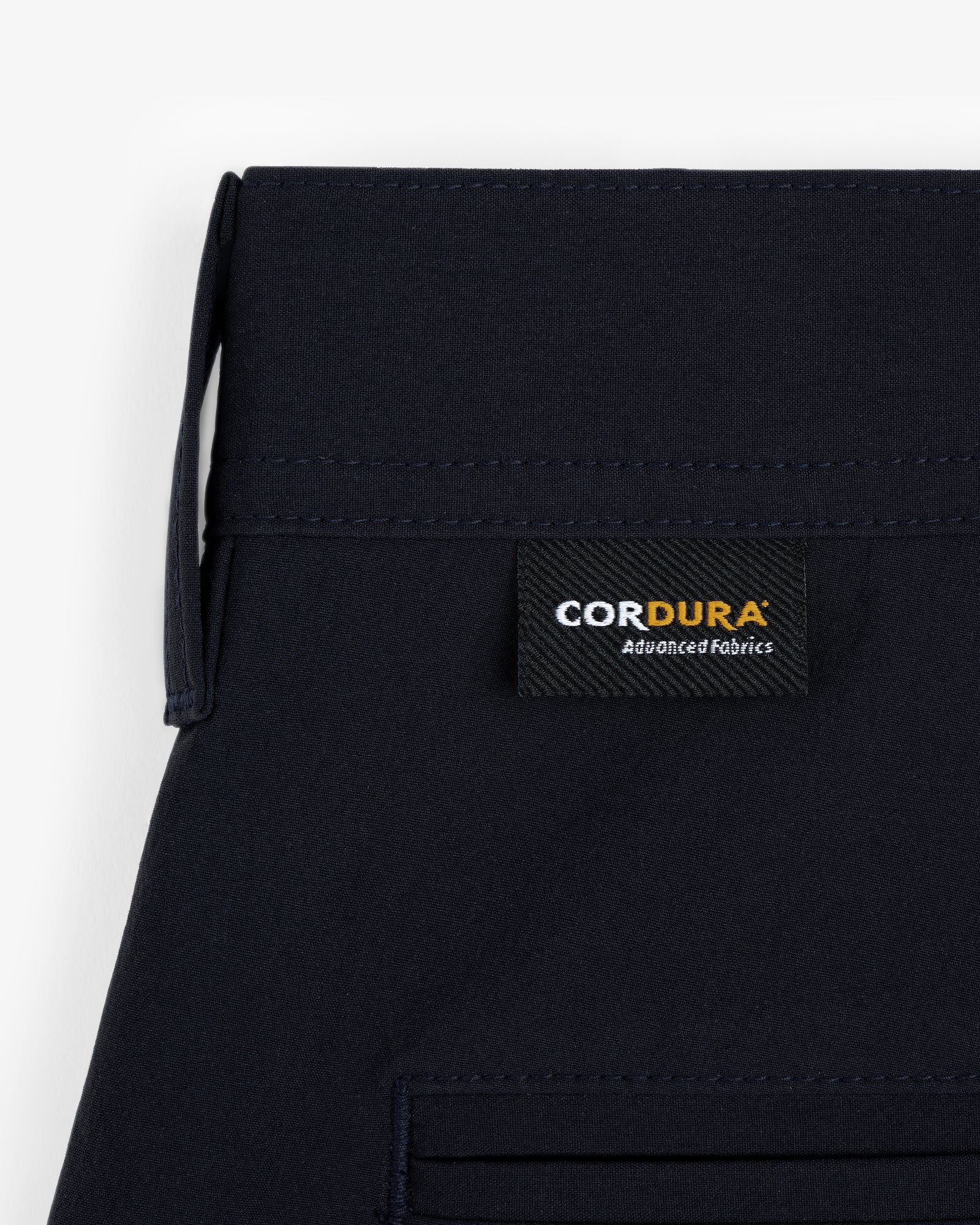 Close-up of ALD Golf Cordura Double Pleated Short in navy with a black CORDURA Advanced Fabrics label sewn on.