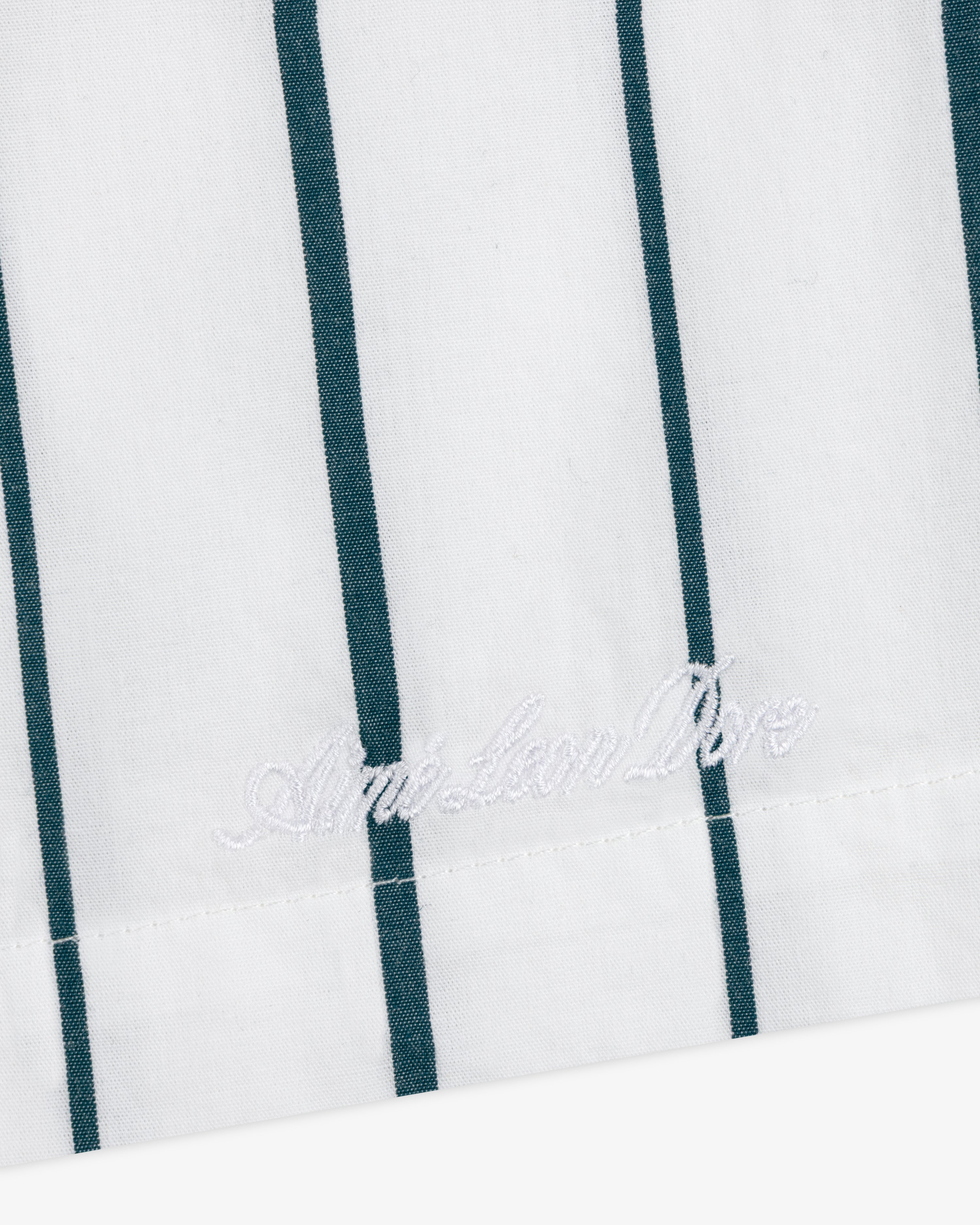 White poplin leisure shorts with vertical green stripes and white "American Dior" embroidery near the edge.