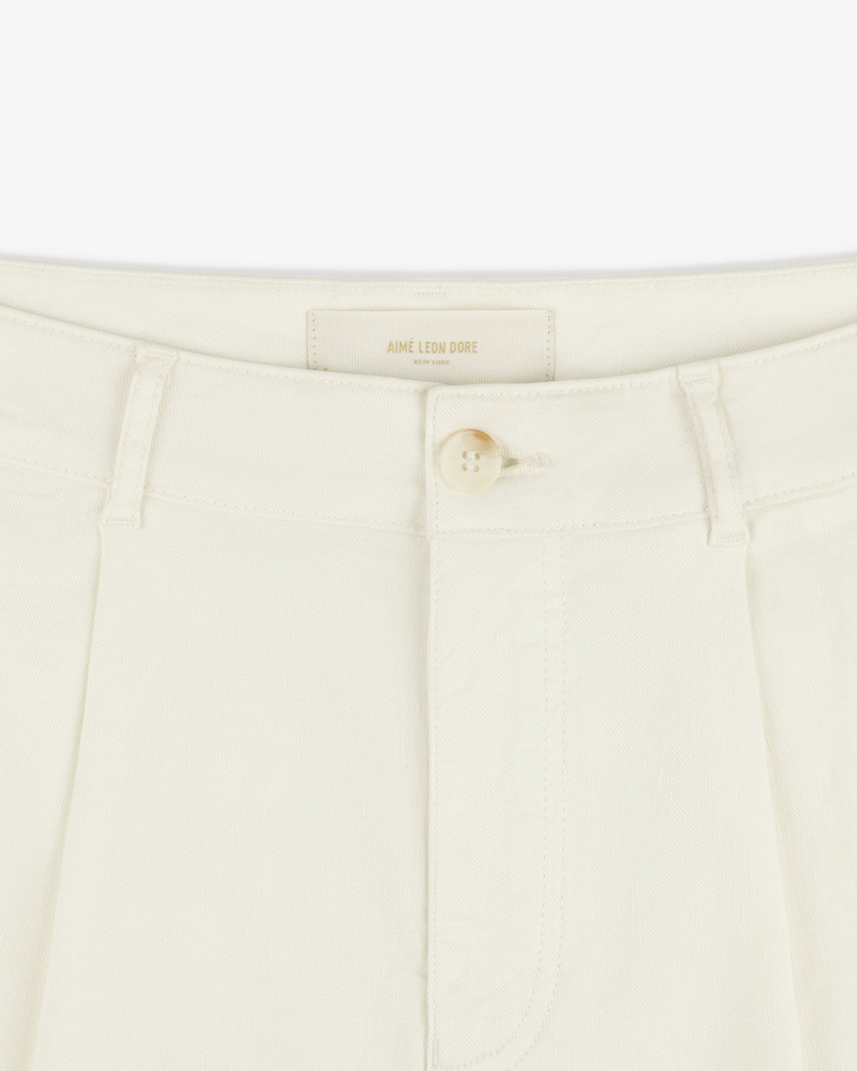 Close-up of Pleated Linen Blend Bermuda Short in cream with button closure, belt loops, and Aime Leon Dore label.