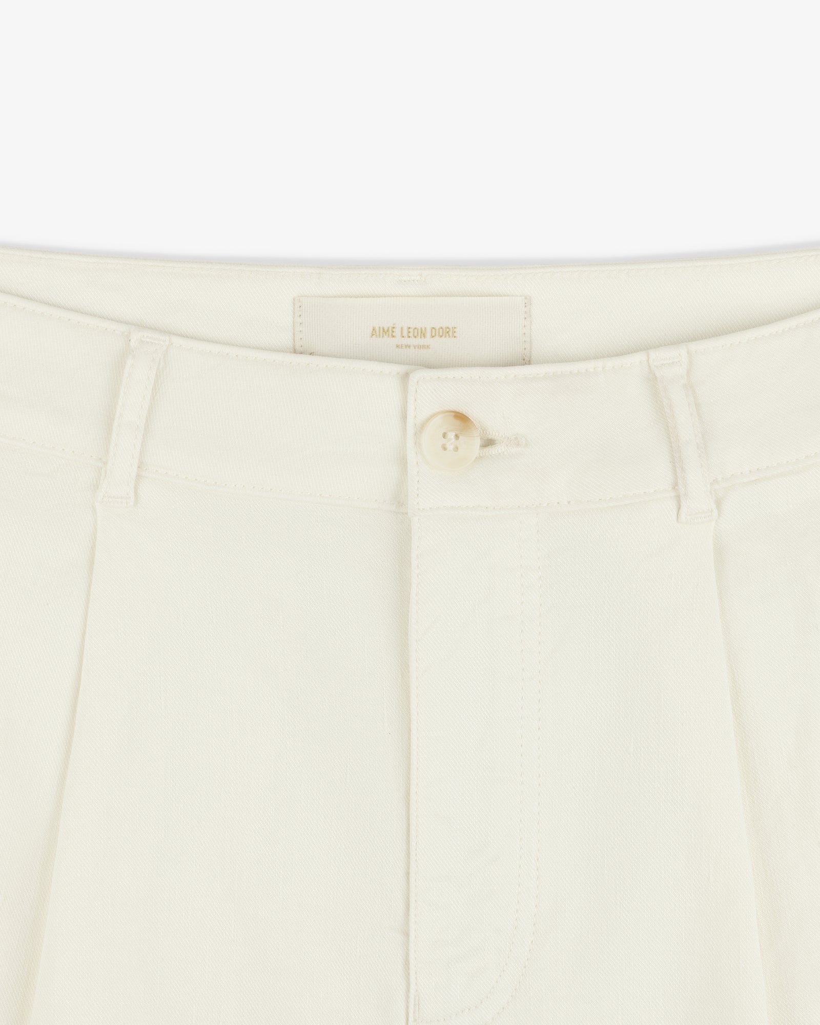 Close-up of Pleated Linen Blend Bermuda Short in cream with button closure, belt loops, and Aime Leon Dore label.