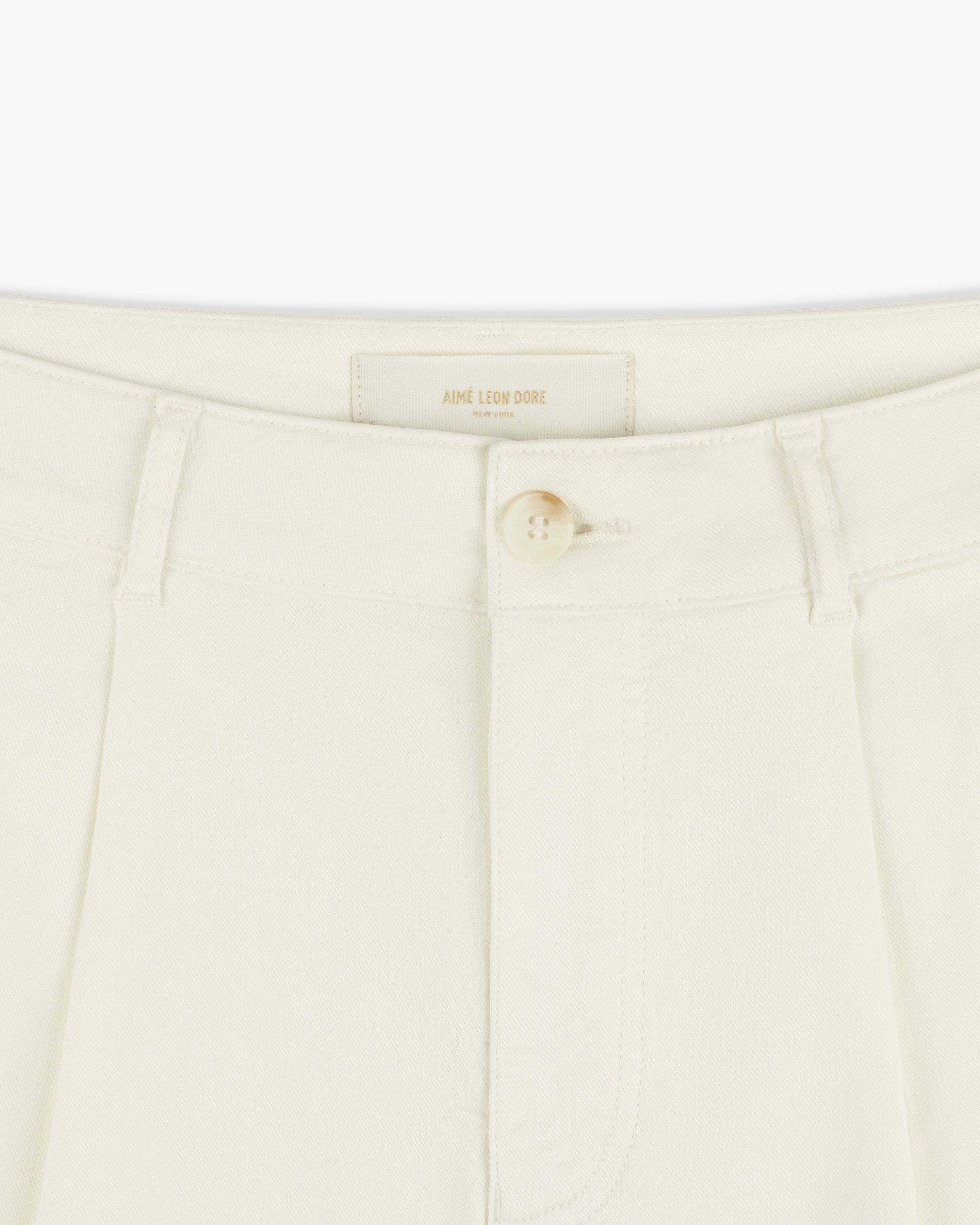 Close-up of Pleated Linen Blend Bermuda Short in cream with button closure, belt loops, and Aime Leon Dore label.