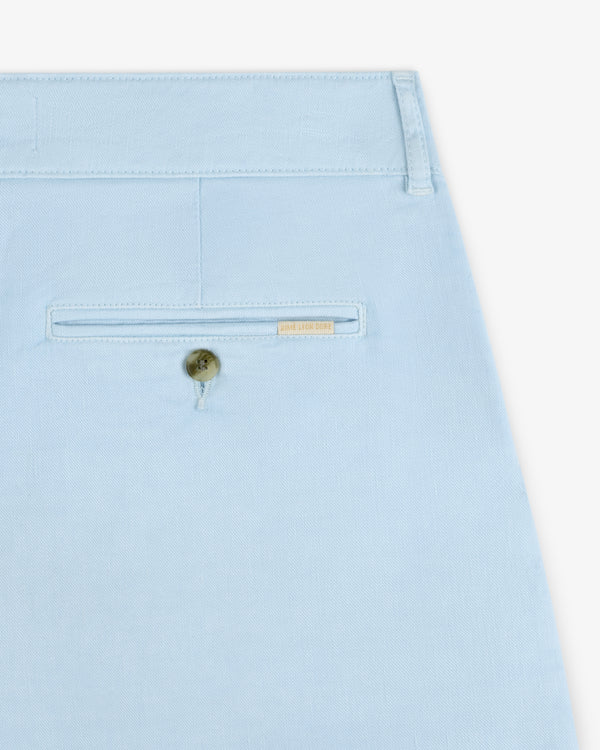 Close-up of the back pocket of Pleated Linen Blend Bermuda Shorts in light blue, with button and beige label above pocket.