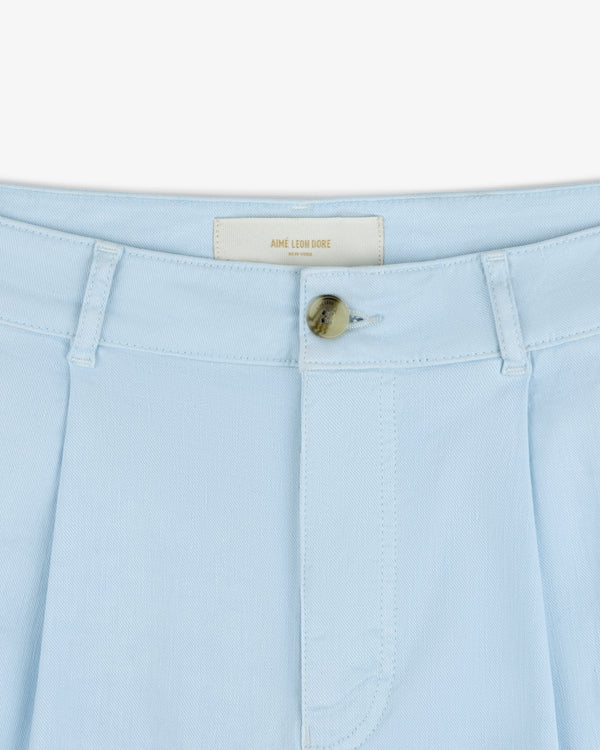 Close-up of Pleated Linen Blend Bermuda Short in light blue with tan button and AIME LEON DORE label inside waistband.