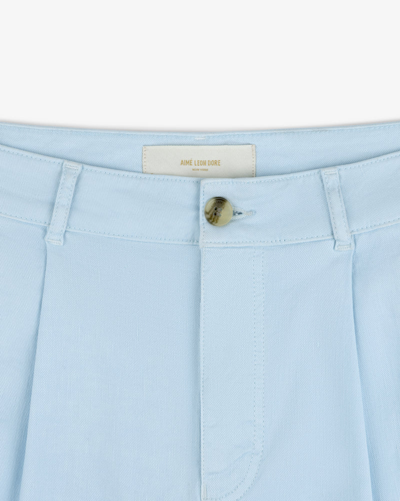Close-up of Pleated Linen Blend Bermuda Short in light blue with tan button and AIME LEON DORE label inside waistband.