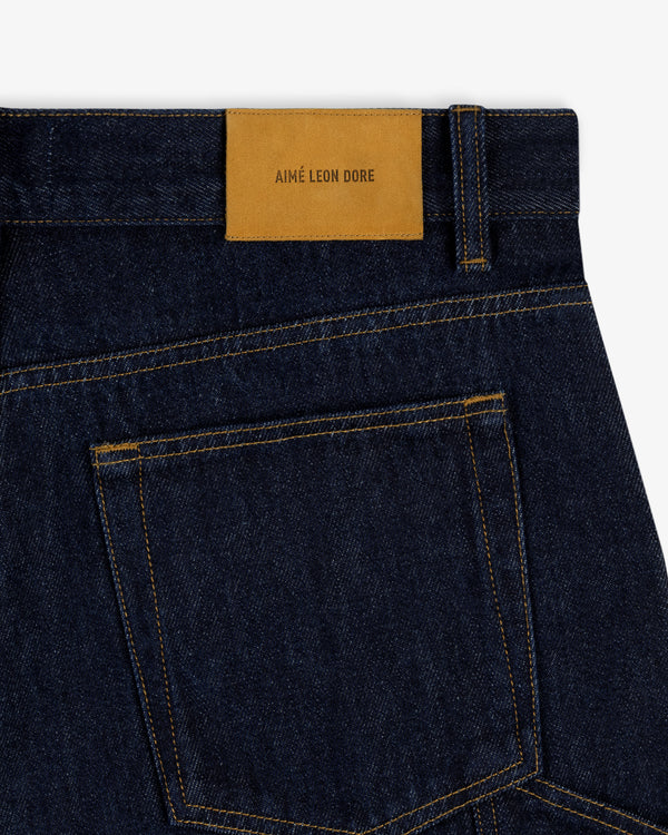 Close-up of Rinse Wash Denim Short with a tan leather Aimé Leon Dore label above the back pocket.