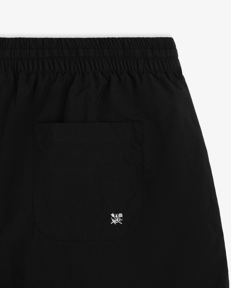 Close-up of Long Nylon Track Short in black with elastic waistband and back pocket featuring white embroidered logo.