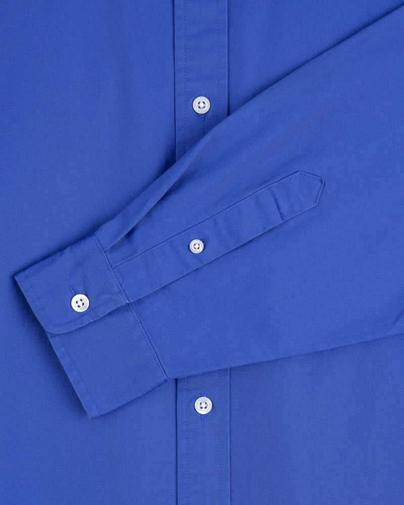 Close-up of the Leon Overshirt, a long-sleeve blue button-up with white buttons, showing the front and sleeve.