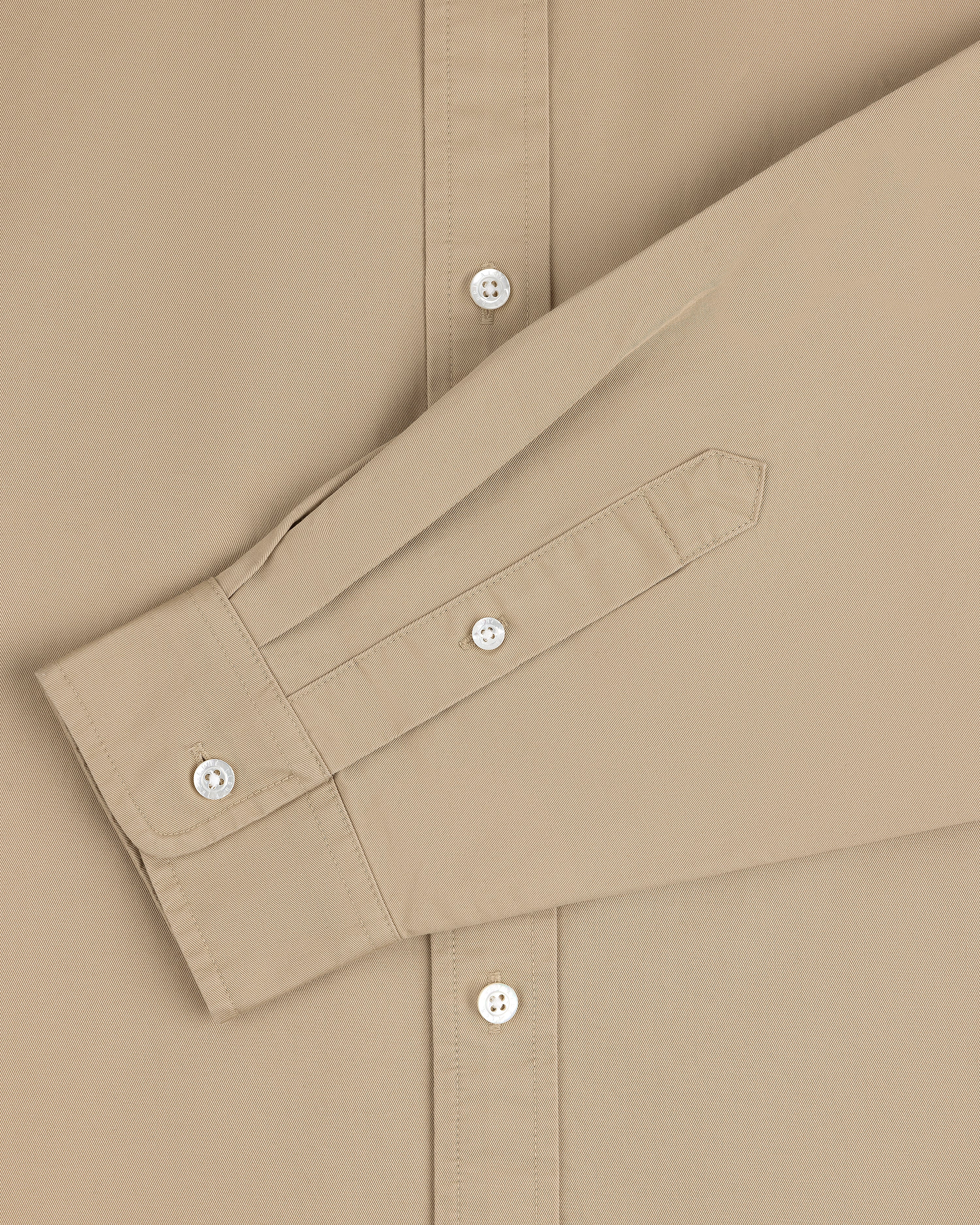 Leon Overshirt in beige with white buttons, styled with the sleeve folded across the front.