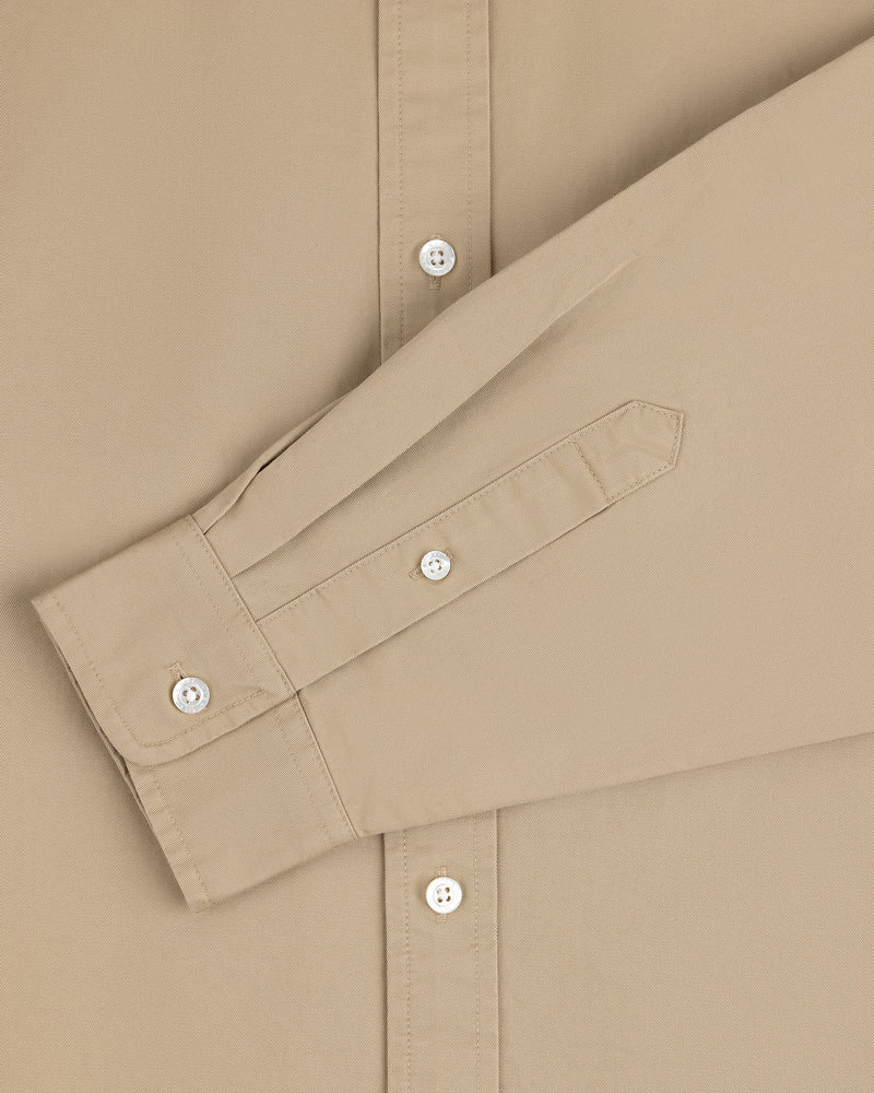 Leon Overshirt in beige with white buttons, styled with the sleeve folded across the front.