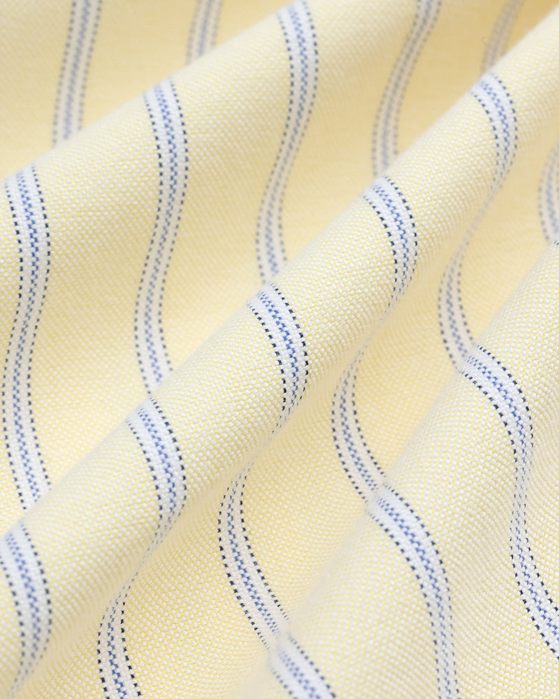 Close-up of the Yarn Dyed Striped Crest Shirt’s yellow fabric with thin blue wavy stripes and textured weave.
