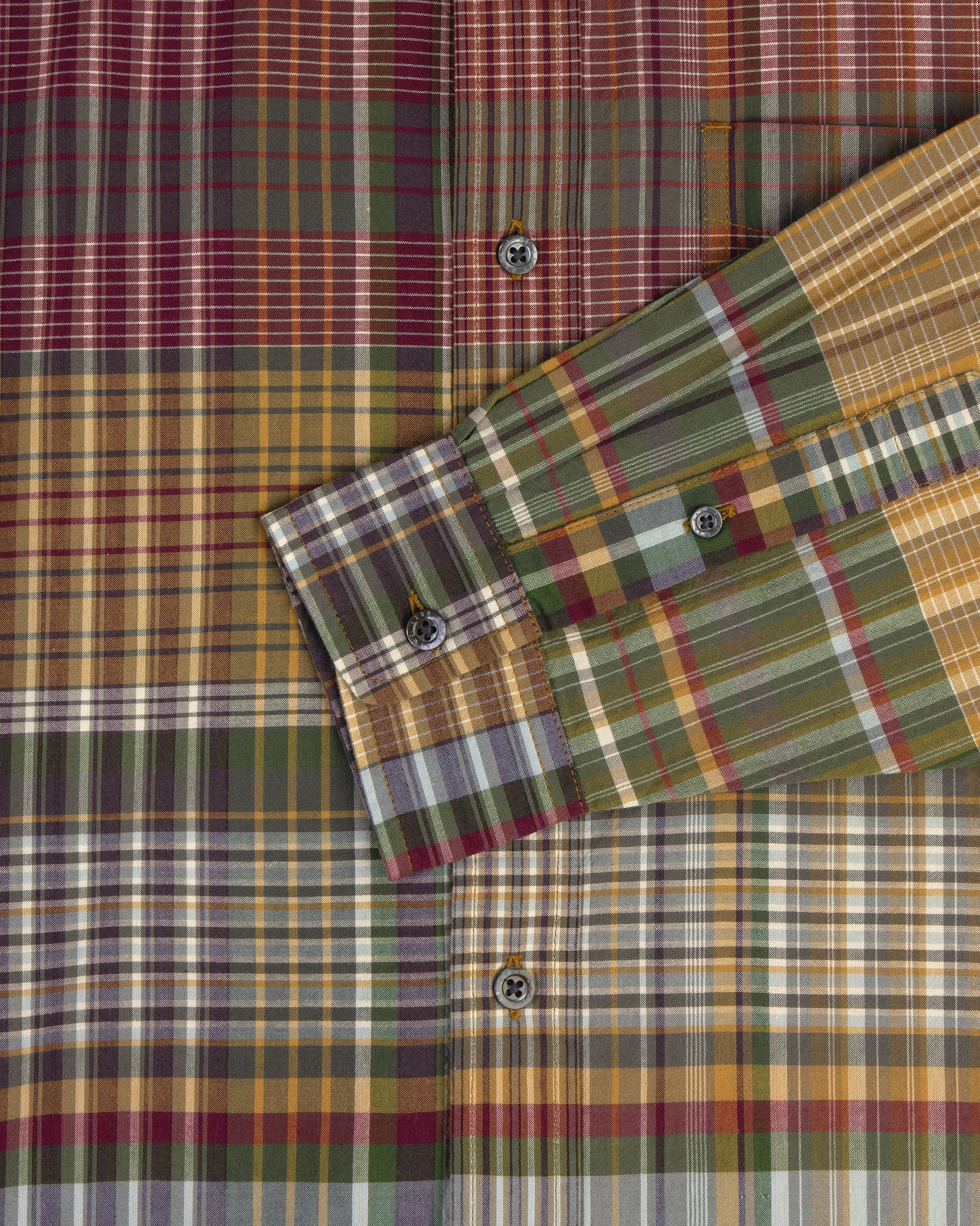 A close-up of the Washed Madras Shirt, featuring green, yellow, red, and white plaid with a folded sleeve.