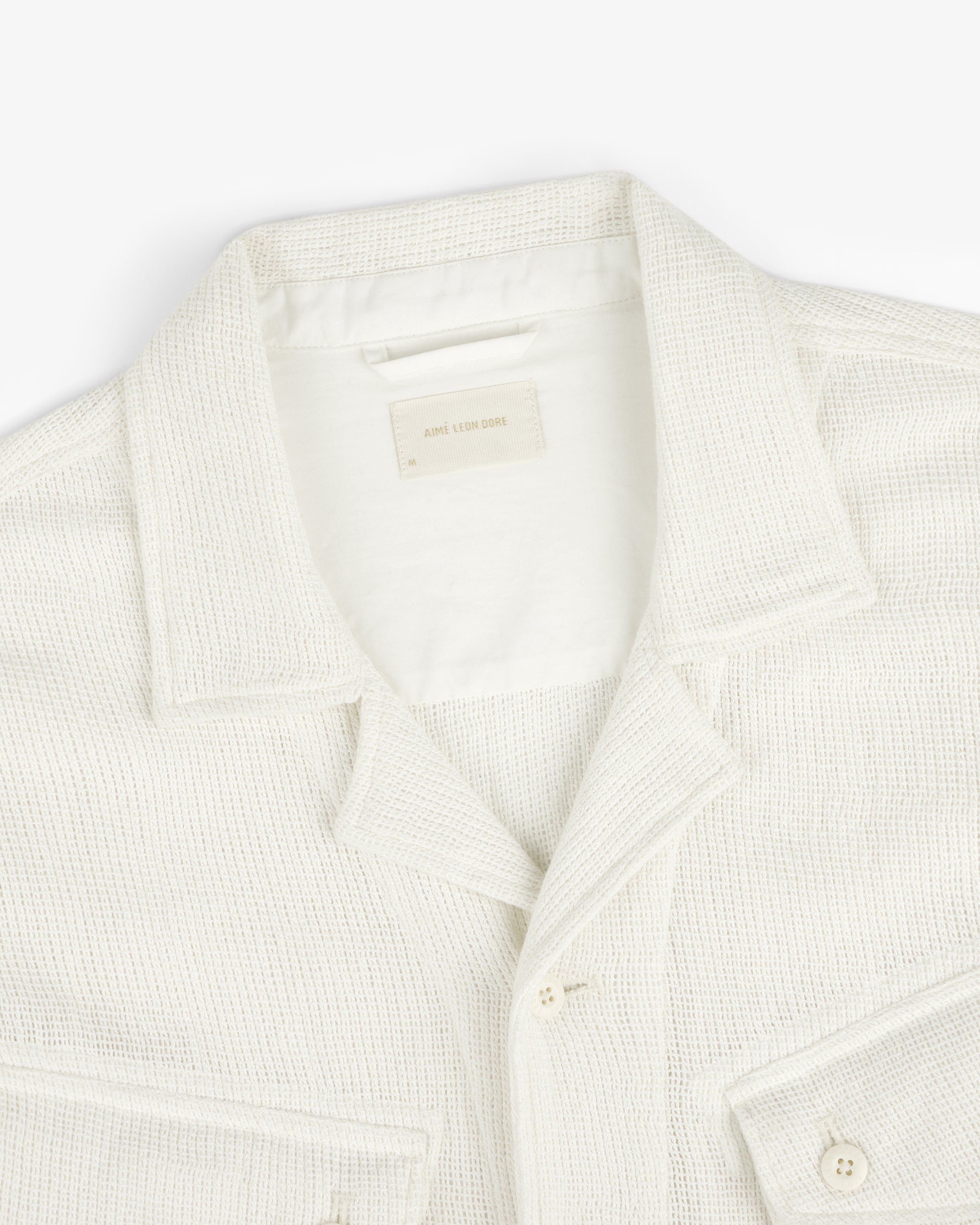 Mesh Jungle Shirt in cream, textured with front pockets, displayed from above on a white background.
