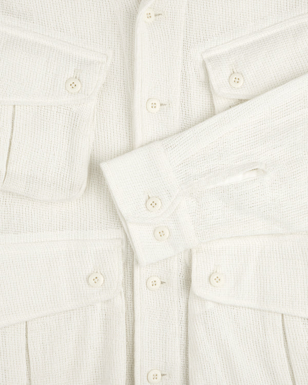 Close-up of the Mesh Jungle Shirt: textured cream fabric, white buttons, two chest pockets, one sleeve across the front.