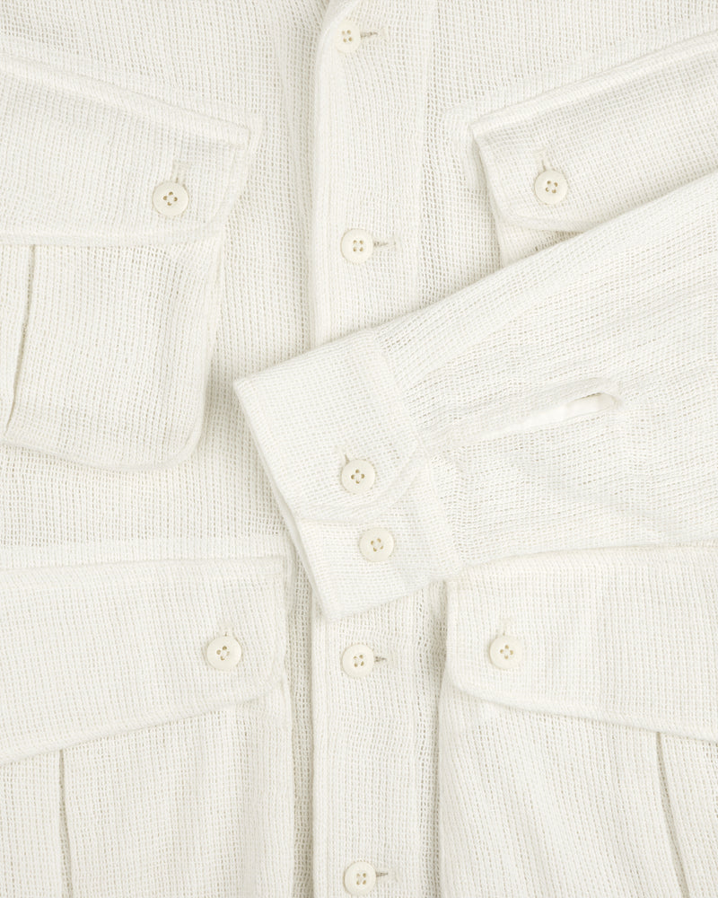 Close-up of the Mesh Jungle Shirt: textured cream fabric, white buttons, two chest pockets, one sleeve across the front.