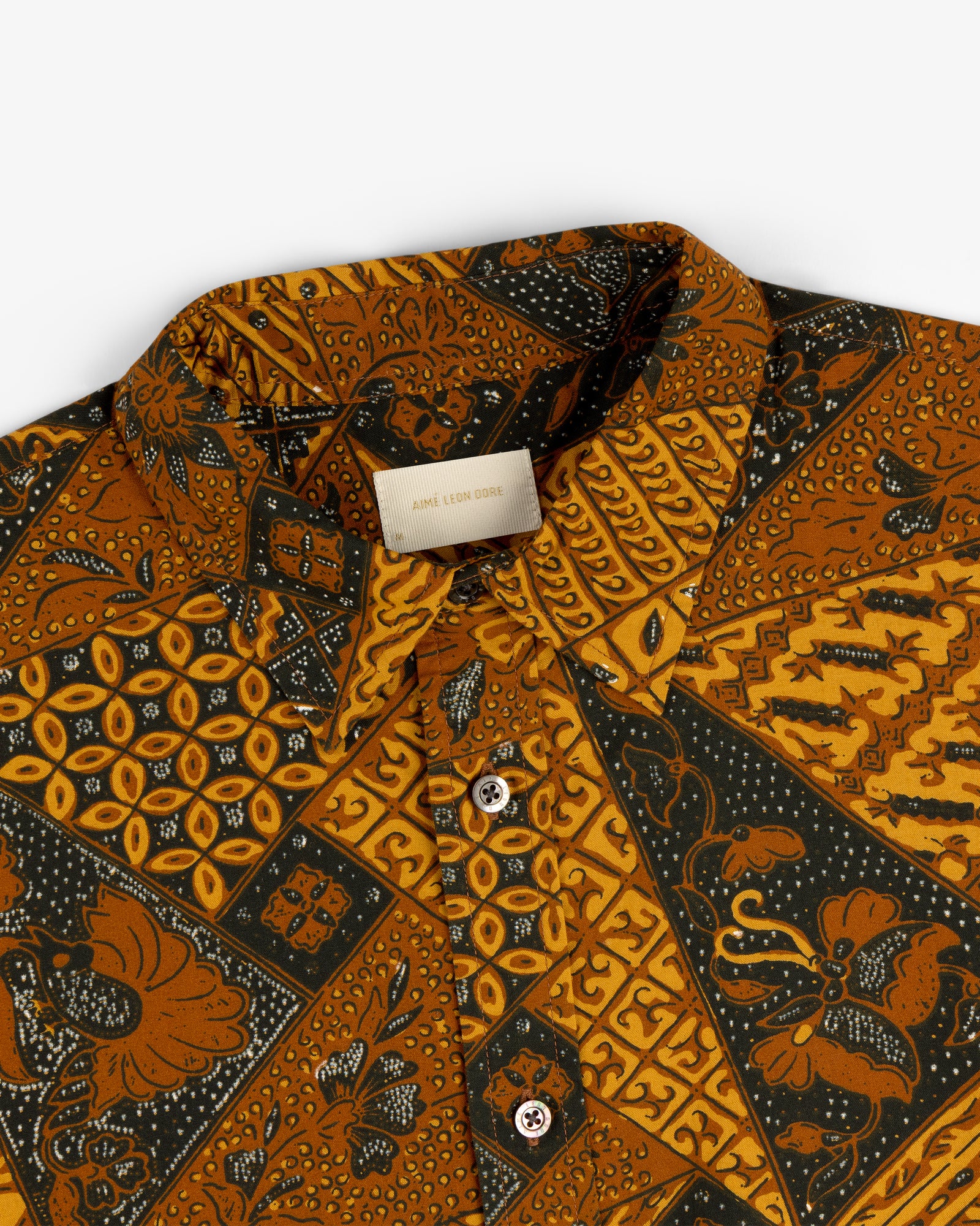 Close-up of Printed Abstract Shirt featuring brown, yellow, and black geometric and floral patterns.