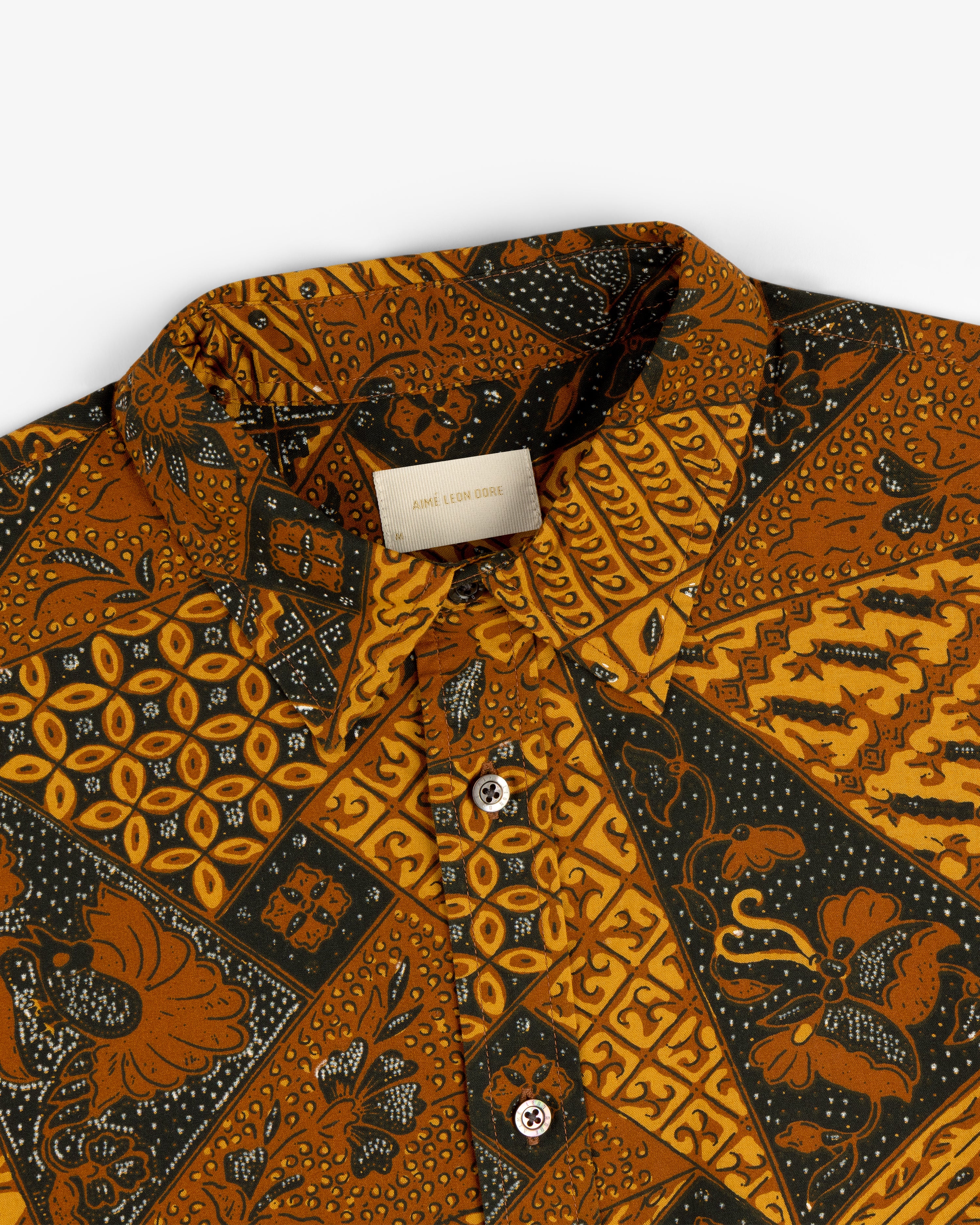 Close-up of Printed Abstract Shirt featuring brown, yellow, and black geometric and floral patterns.