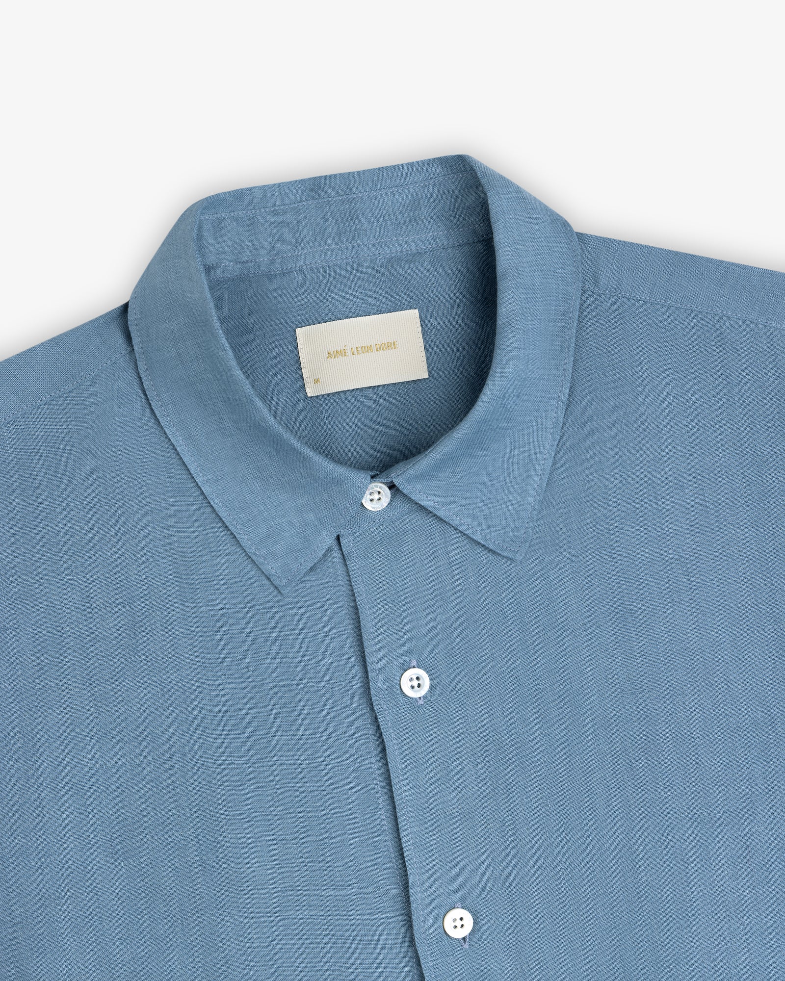 Light blue Long-Sleeve Linen Shirt with a collar, white buttons, and a beige neck label on a plain background.