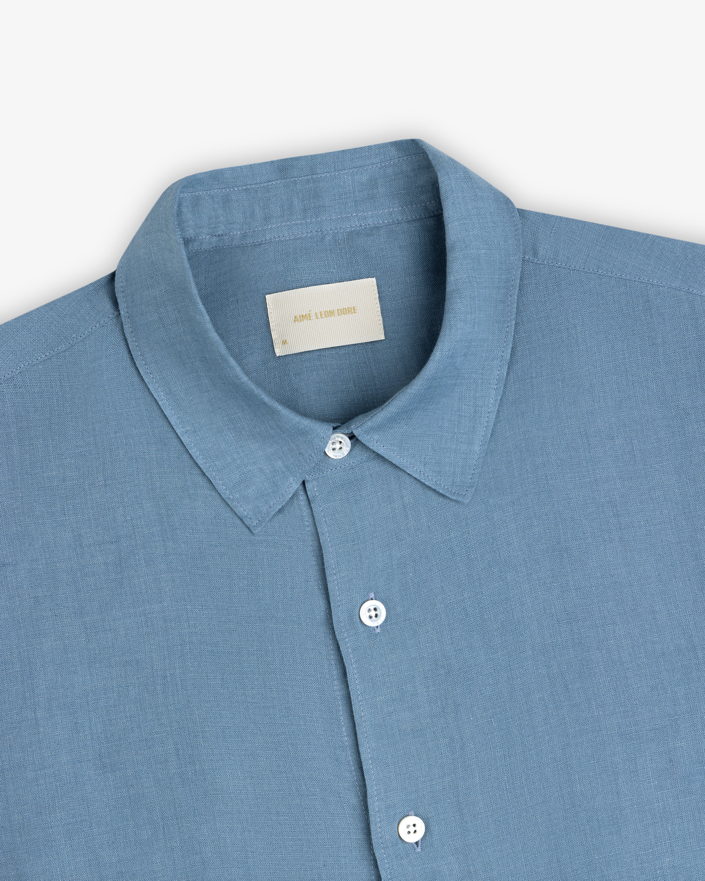 Light blue Long-Sleeve Linen Shirt with a collar, white buttons, and a beige neck label on a plain background.